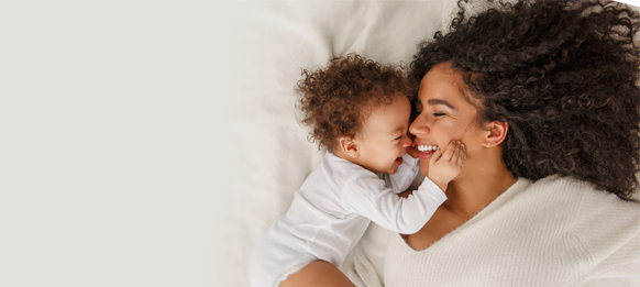 Woman and toddler lying on bed cuddling